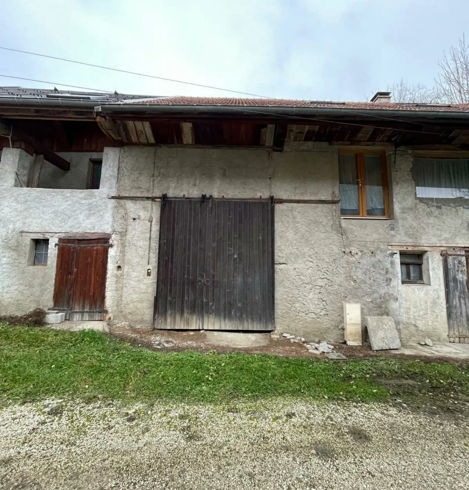 Façade sud d'une ancienne ferme à Entrelacs avec sa porte de grange, avant travaux